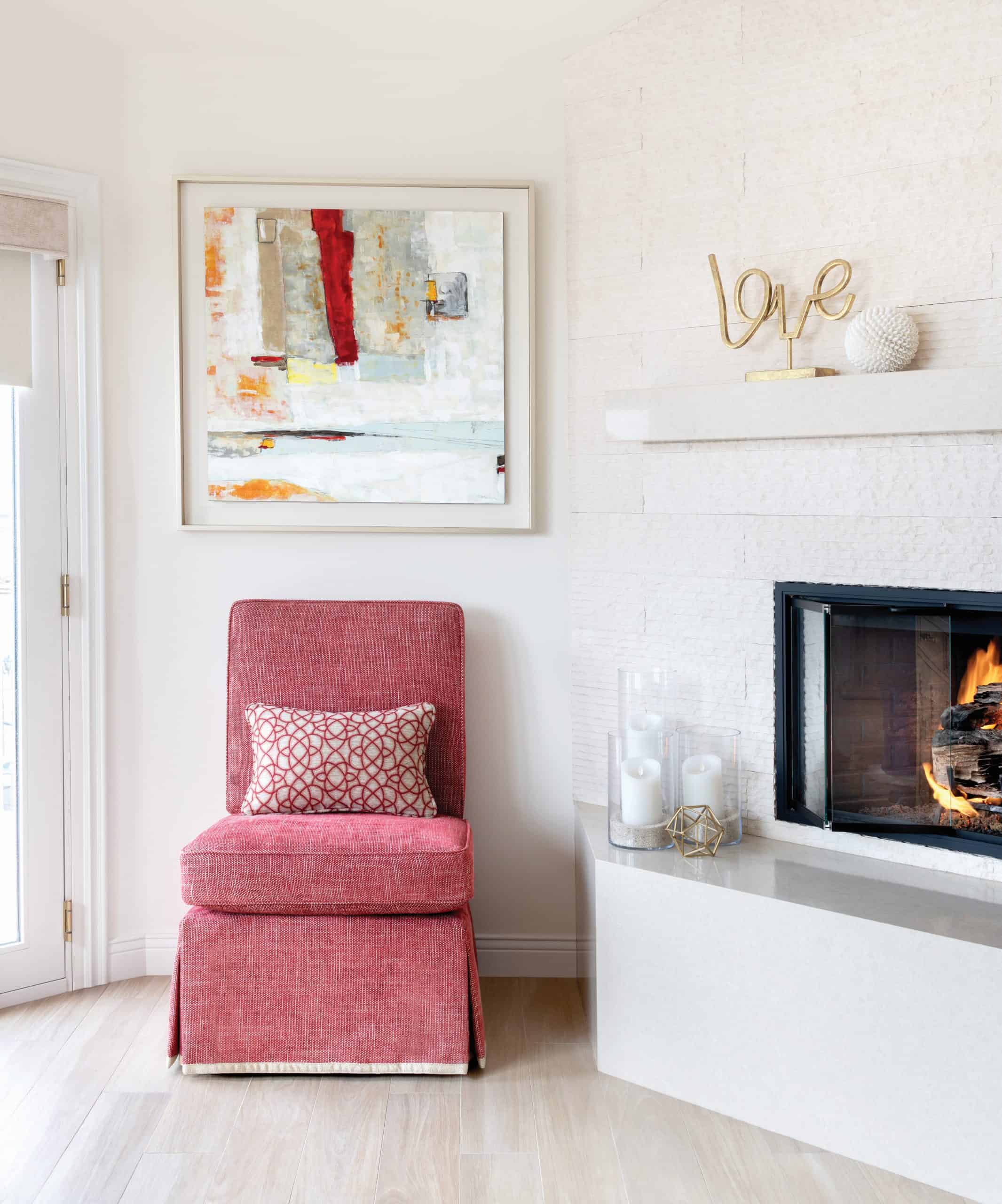 Bright and beachy living room with whitewashed corner fireplace with red upholstered side chair in Manhattan Beach