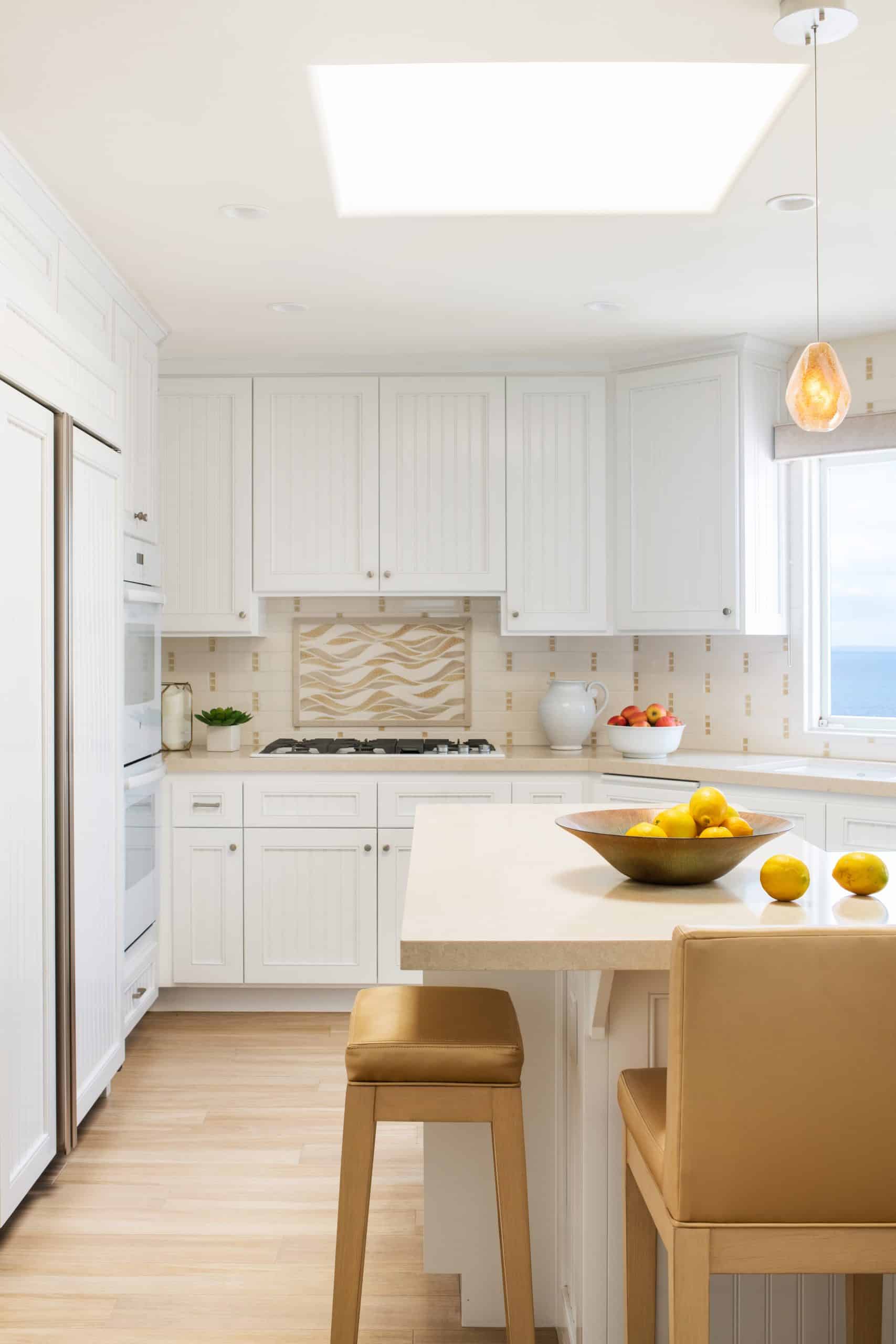 Beachy contemporary kitchen with white cabinets and neutral upholstered stools in Manhattan Beach